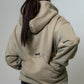 A person shown from the back wearing a light beige oversized dog training hoodie with a small black 'MALIKO' logo on the upper back