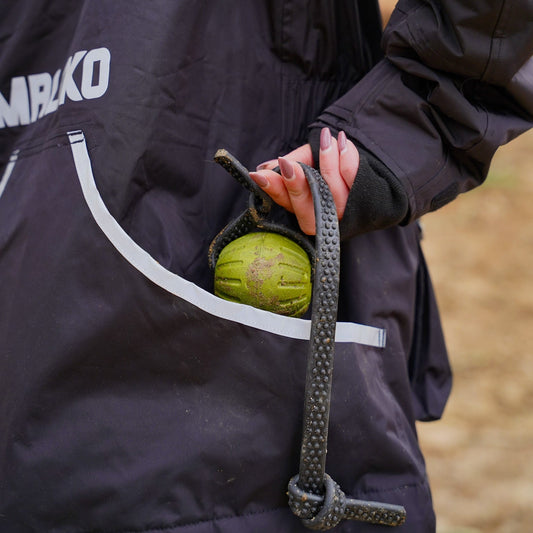 Person holding a green ball with a rope, wearing a black jacket with MALIKO branding.